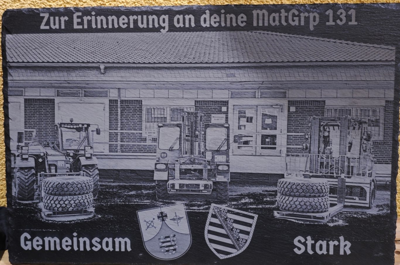Gravierte Gedenktafel mit Text und Symbolen zur Erinnerung an die MatGrp 131.